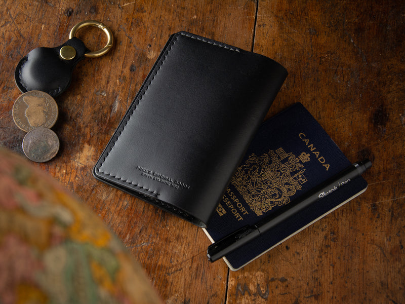 back of black passport wallet sitting on a table with keychain and coins