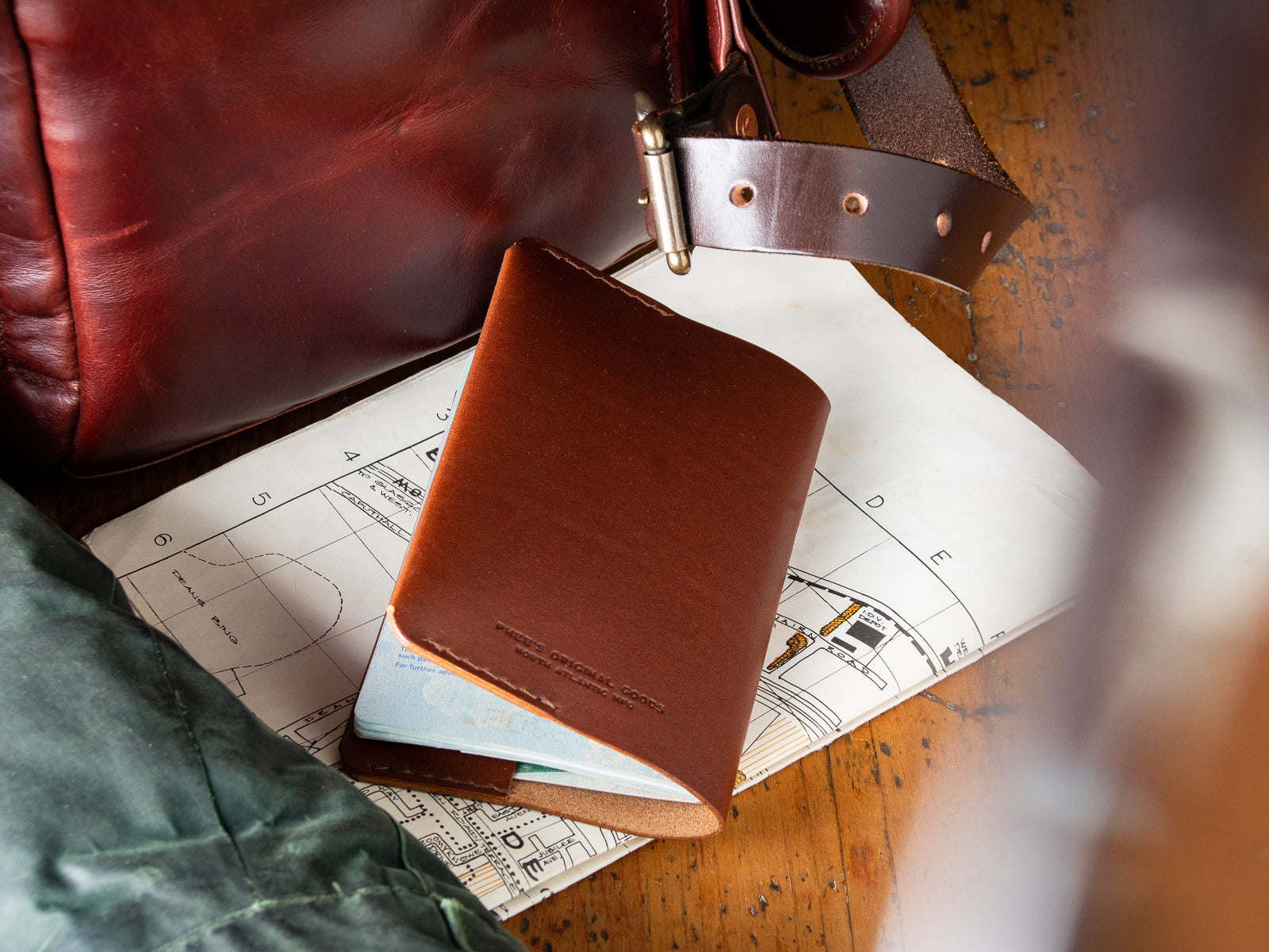 A brown passport Wallet sitting beside a backpack and map ready for an overseas trip