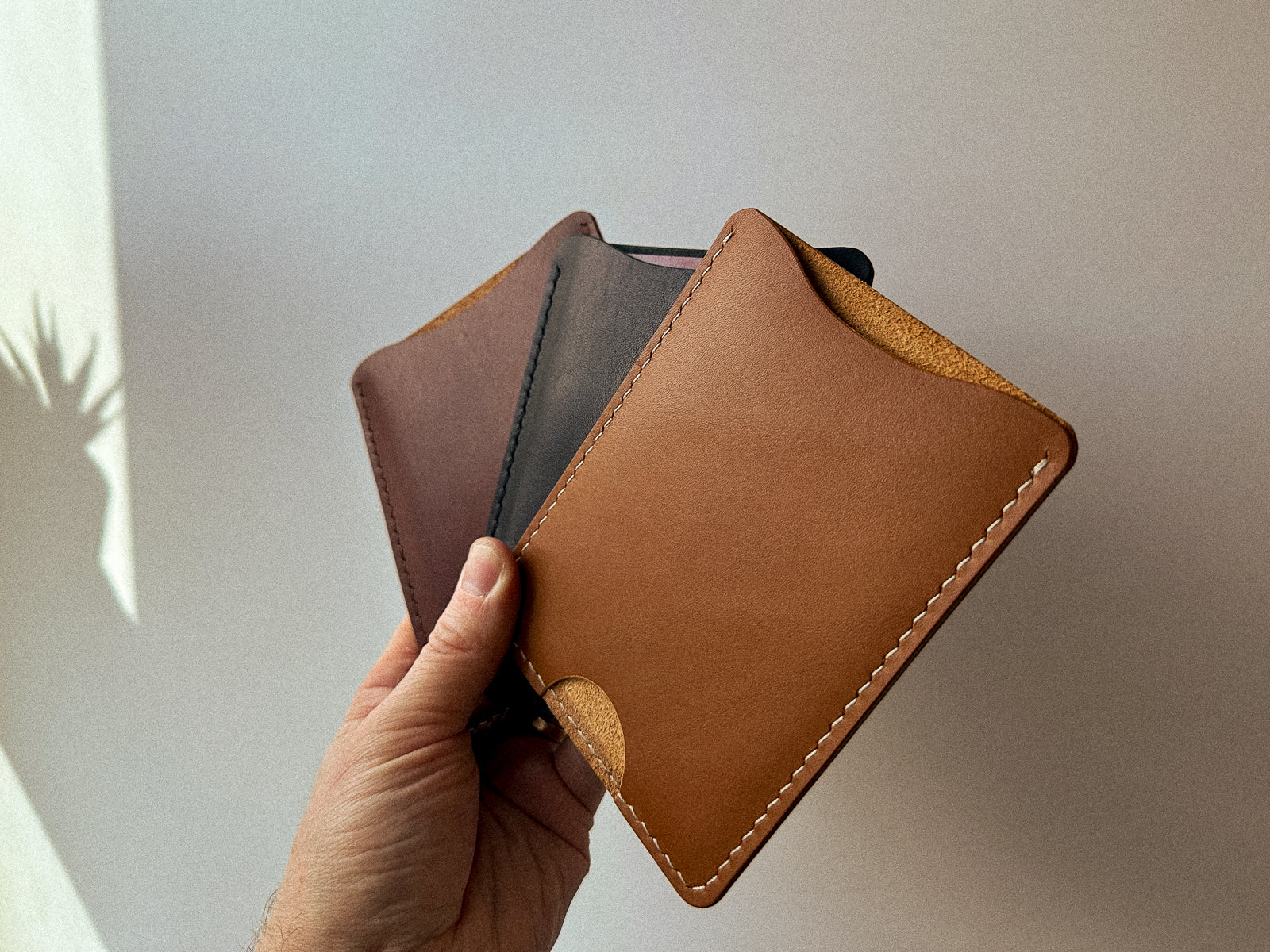 brown, black and tan leather passport slips held in hand