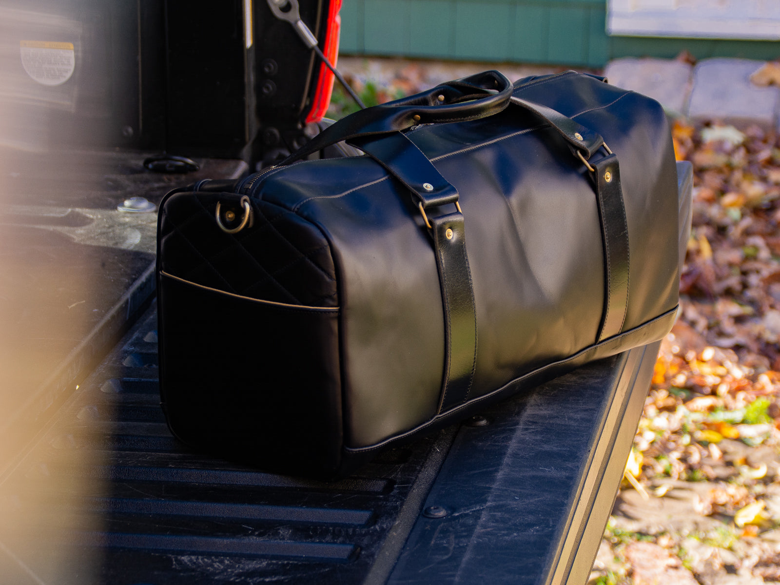 Reserve leather duffel bag in all black sitting on the tailgate of a truck.