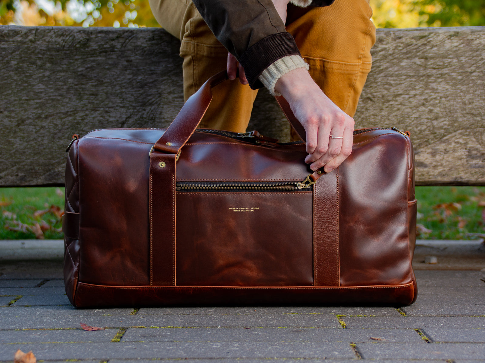 The front view of the Reserve Duffel Bag and its front zippered pocket with gold embossed emblem.