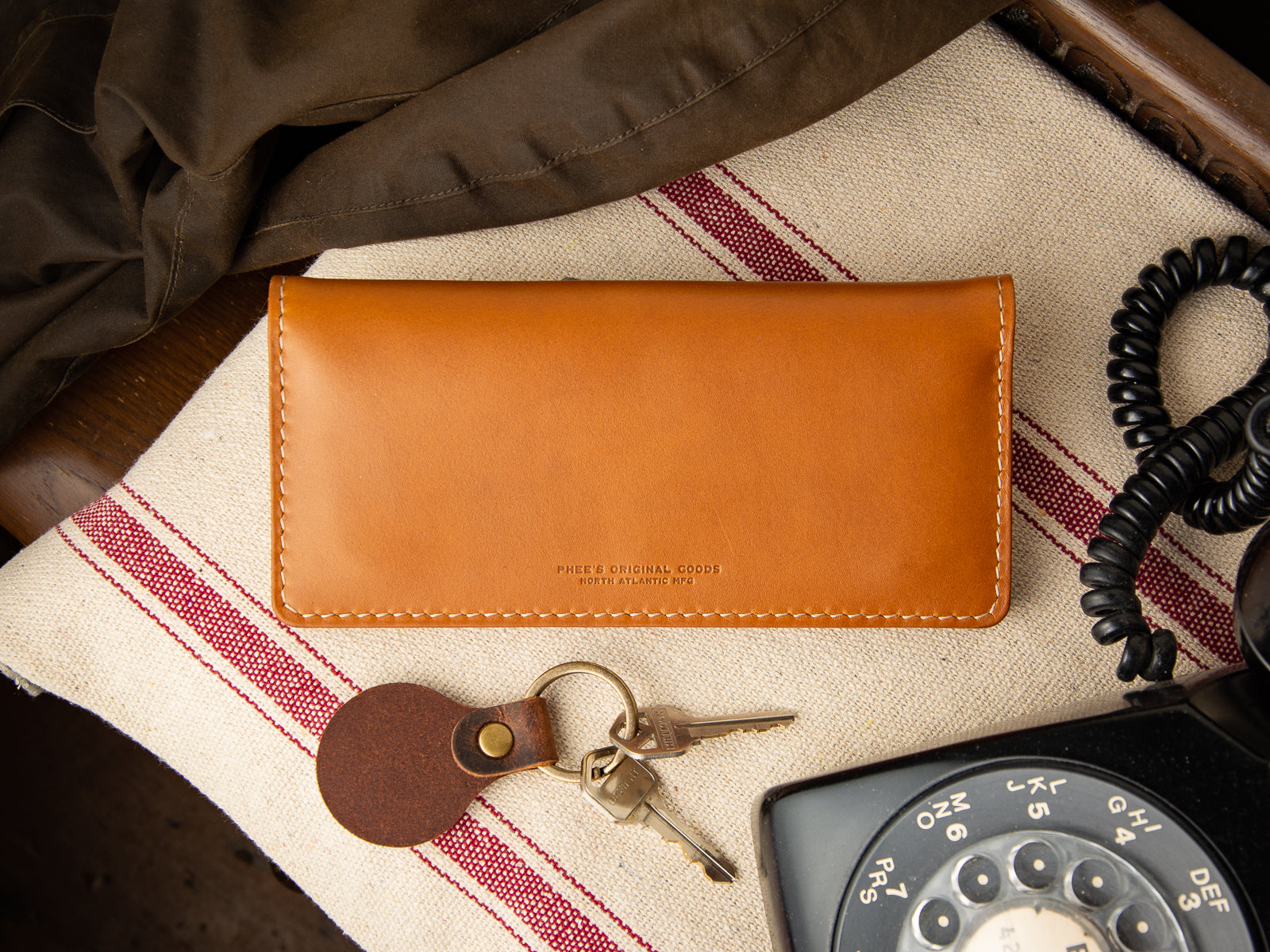 Clutch wallet in tan full grain leather sitting on phone table in foyer.