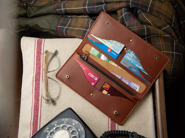 Brown veg-tan leather Rosedale clutch wallet, laying on an entry table, full of cards