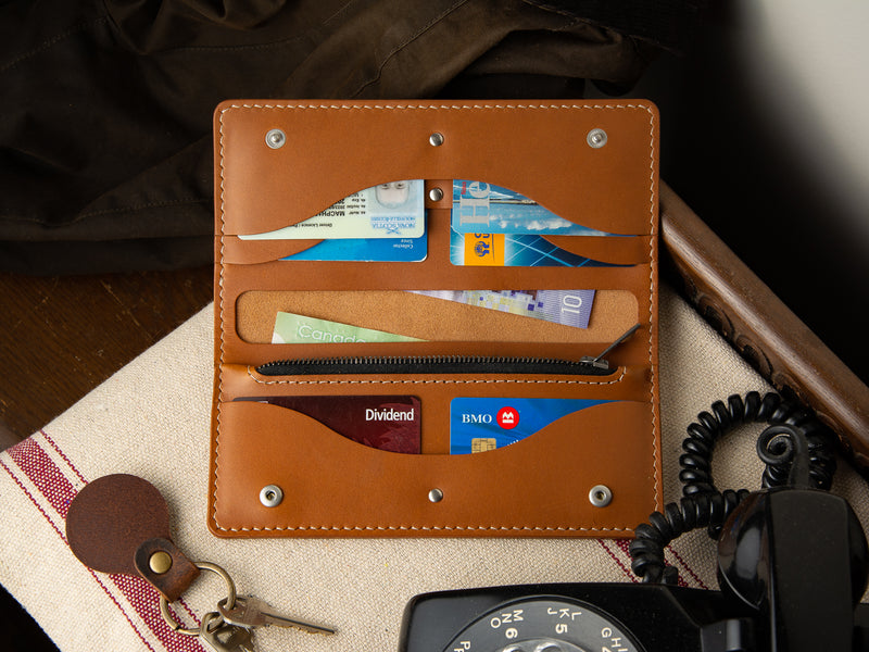 Tan full grain leather Rosedale clutch wallet, laying on an entry table, full of cards