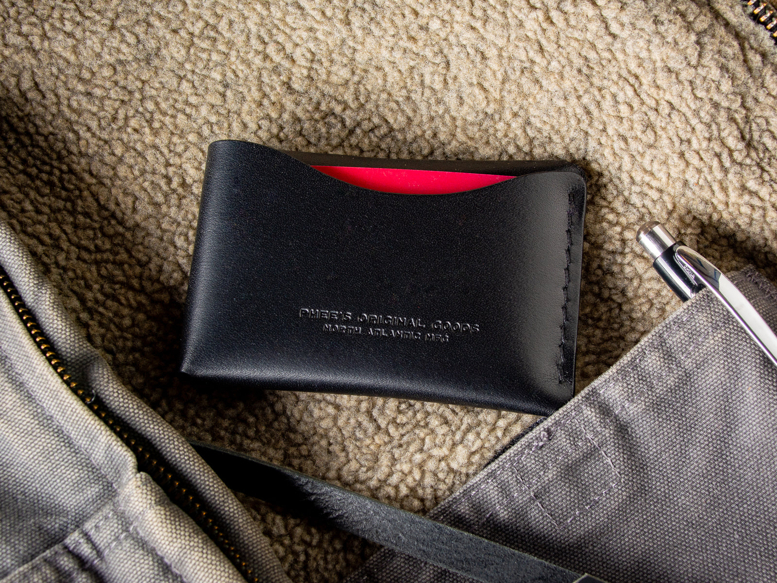 Black Schooner fold wallet sitting inside a wool vest pocket