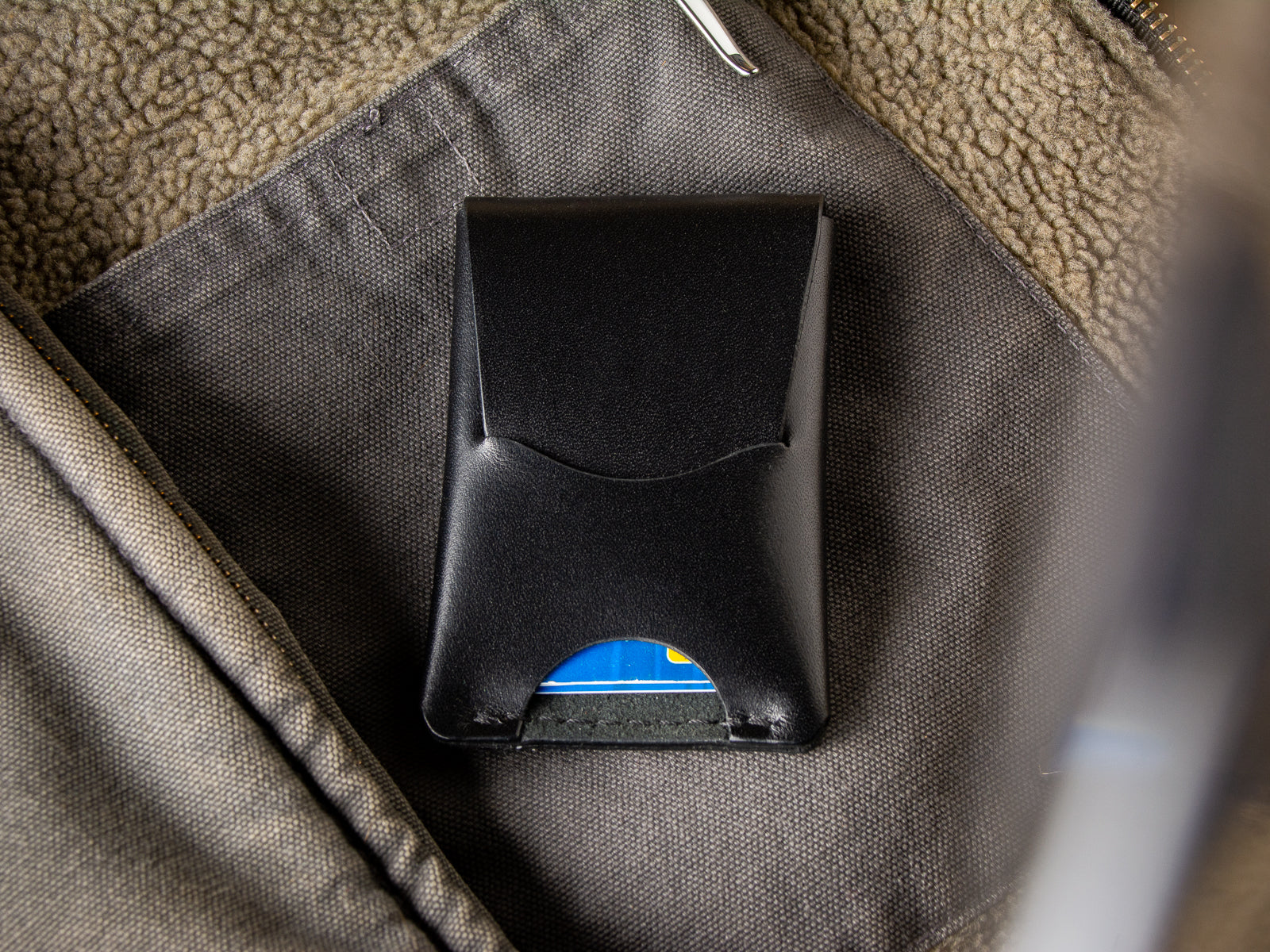 Black Schooner fold wallet sitting inside a wool vest