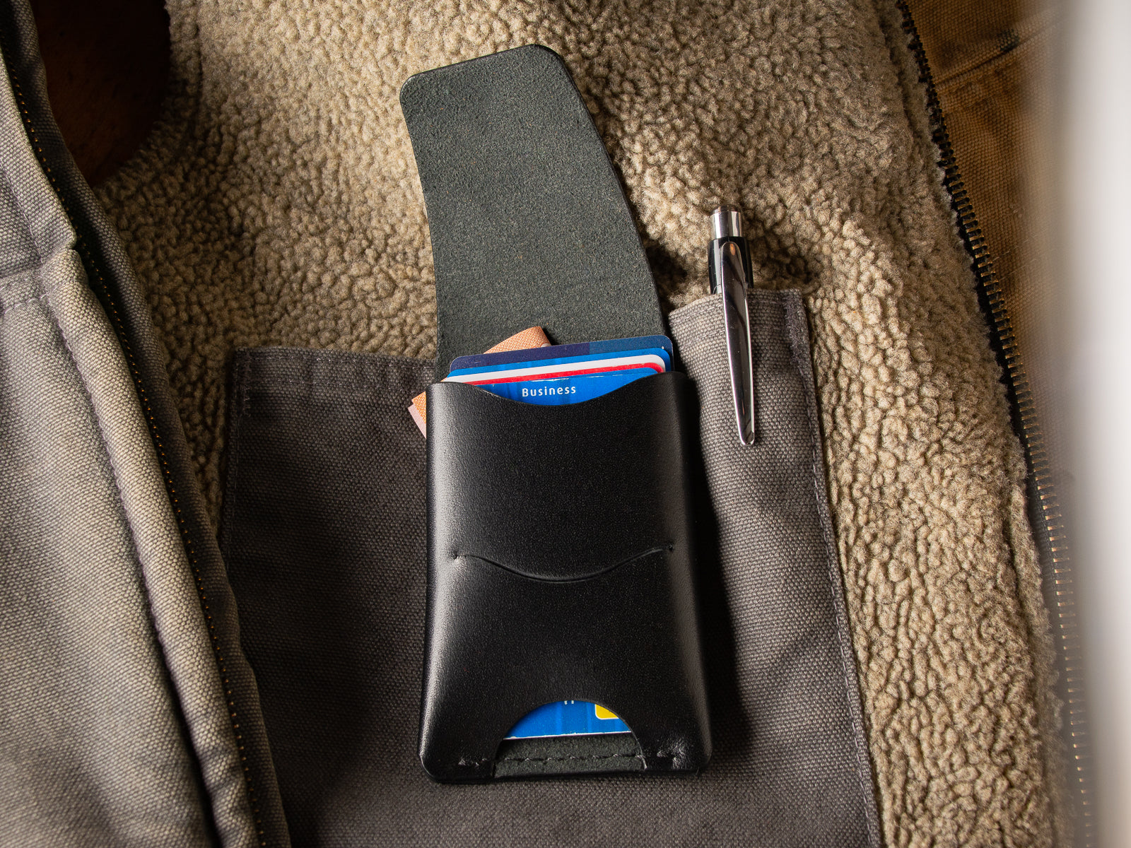 Black Schooner fold wallet sitting inside a wool vest showing it's flap open