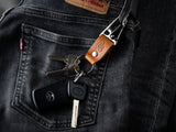 A tan stubby keychain in full grain leather and brass hardware is clasped to a pair of LEvi's denims 