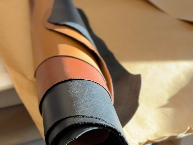 Tan, brown and black veg-tan leather hides rolled up