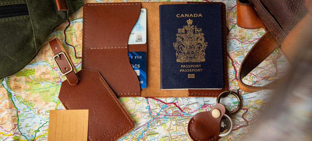 Passport wallet, luggage tag and air tag fob sitting on a map with bags around it