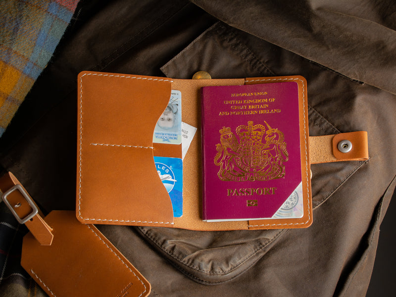 Travel passport wallet in tan full-grain leather sitting open on a jacket