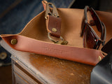 A brown home decor valet tray in full grain leather sitting in a porch 