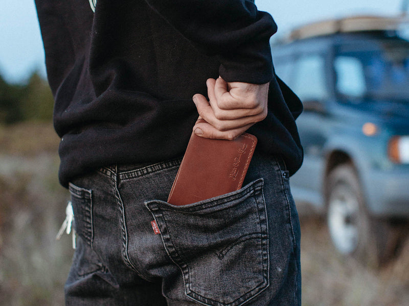 Bucklaw brown leather wallet being put in the back pocket of a pair of Levi's demin jeans