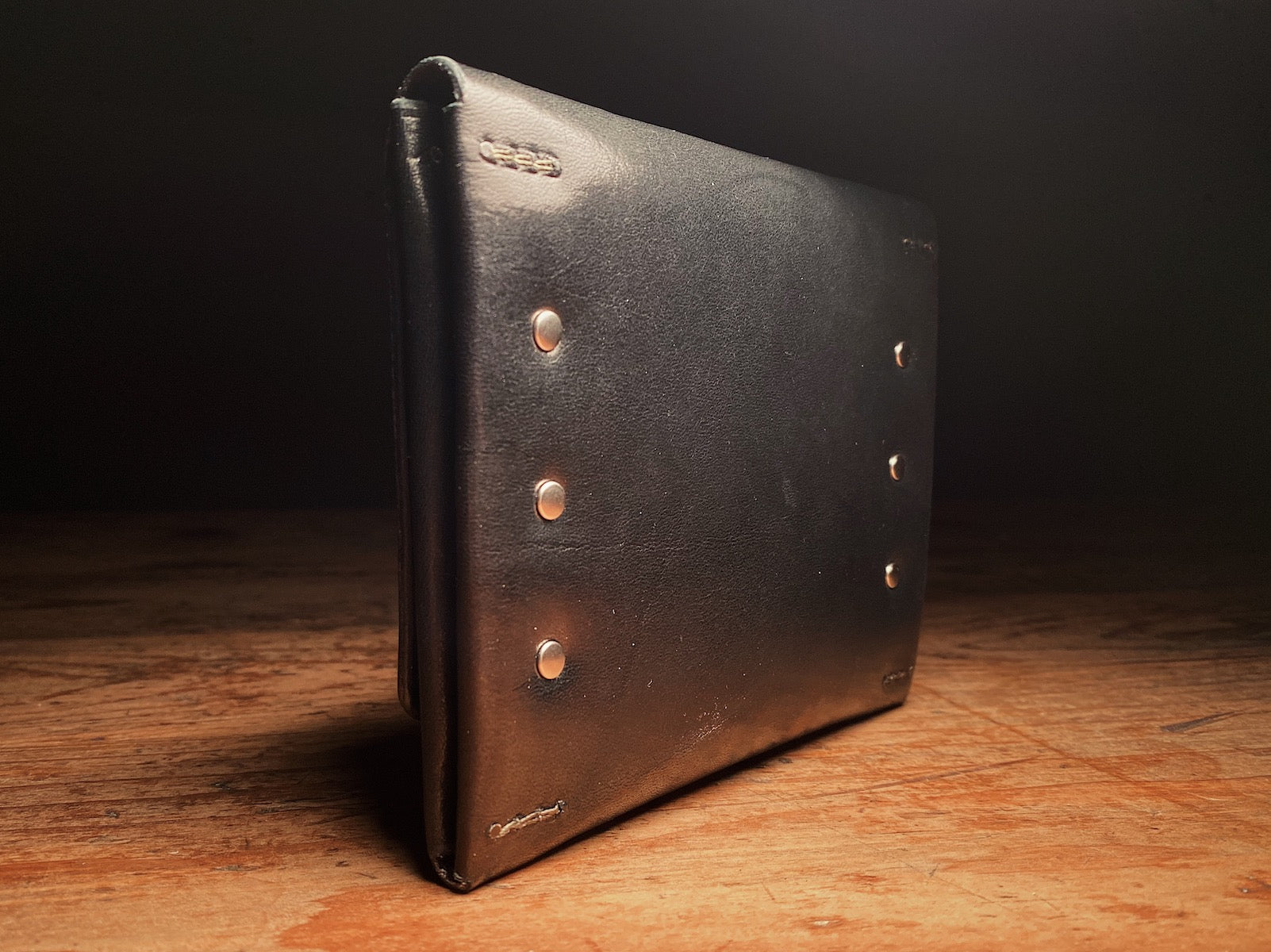 black full-grain harness leather back of the fly fishing wallet, with solid brass hardware
