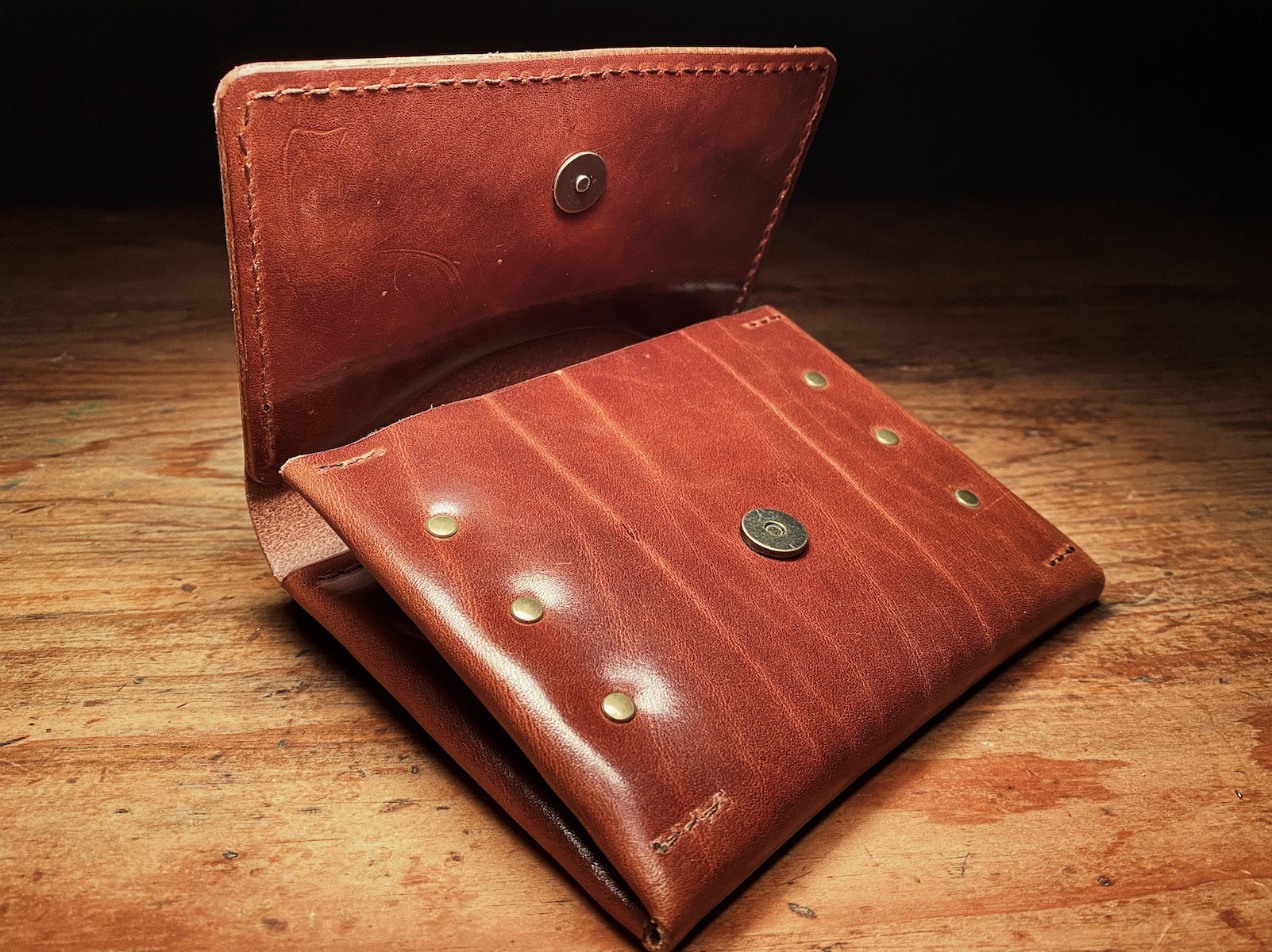 half open fly wallet, showing magnetic closure and natural markings of full-grain brown leather