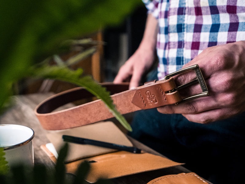 Backside of brown leather Sterling Belt showing debossed logo and handsewn on solid brass buckle