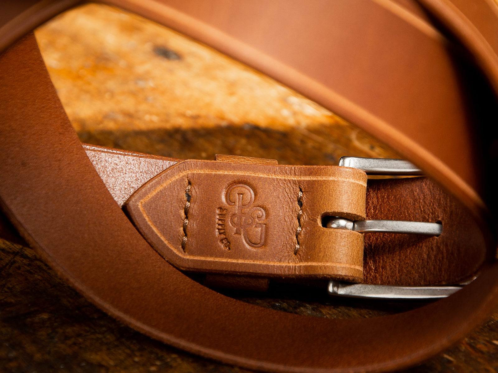 The Sterling Dress Belt in tan shown coiled revealing the embossing and hand stitched detail from the back side.