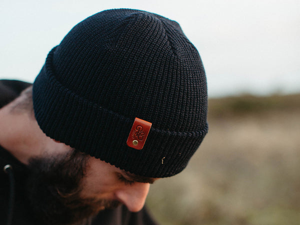 Travis wearing a black supply cuffed toque with brown leather patch
